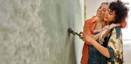 Zwei Frauen die Arm in Arm eine Wand streichen