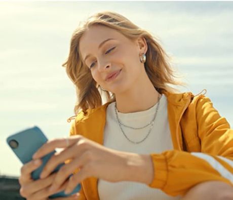 Junge Frau blickt auf Ihr Smartphone Junge Frau am Smartphone